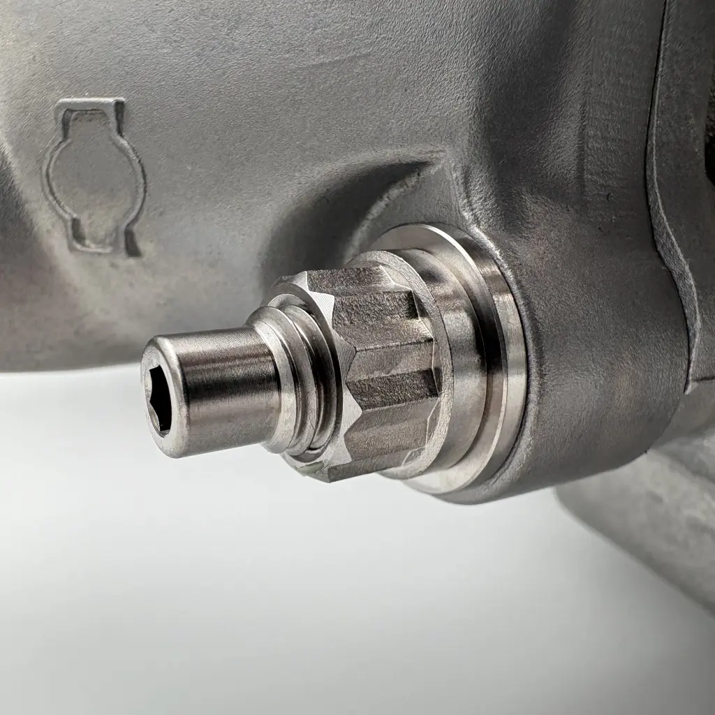 Close-up of the RB26 intake manifold showing the coolant neck with a titanium stud installed through the flange, secured by a titanium washer and nut.